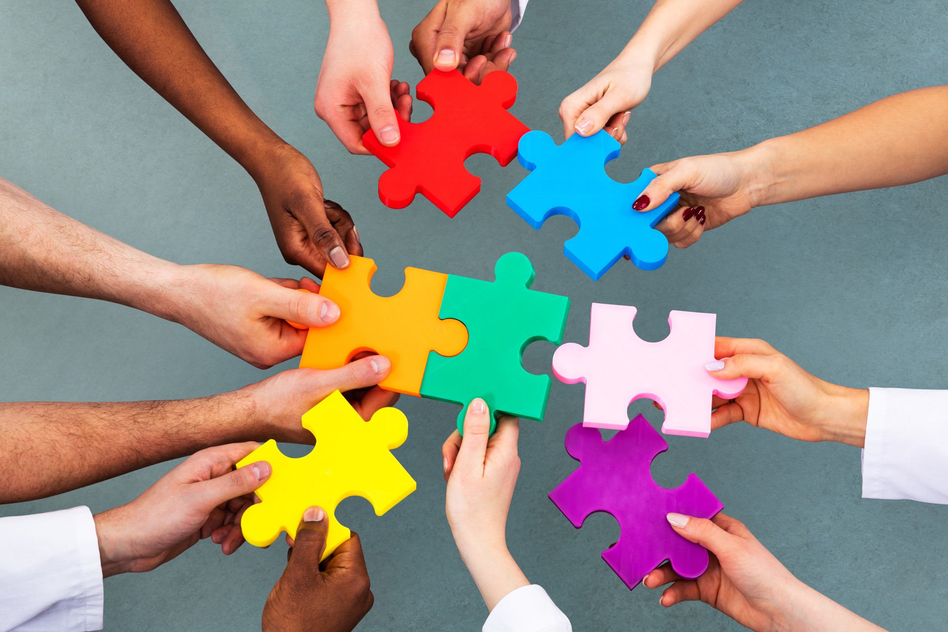 A team of professionals working together to complete a puzzle, symbolising the collaborative effort and problem-solving involved in follow-up audits to achieve lasting change.